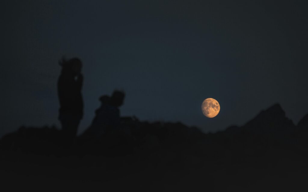 Silhouette of People Standing Under Full Moon